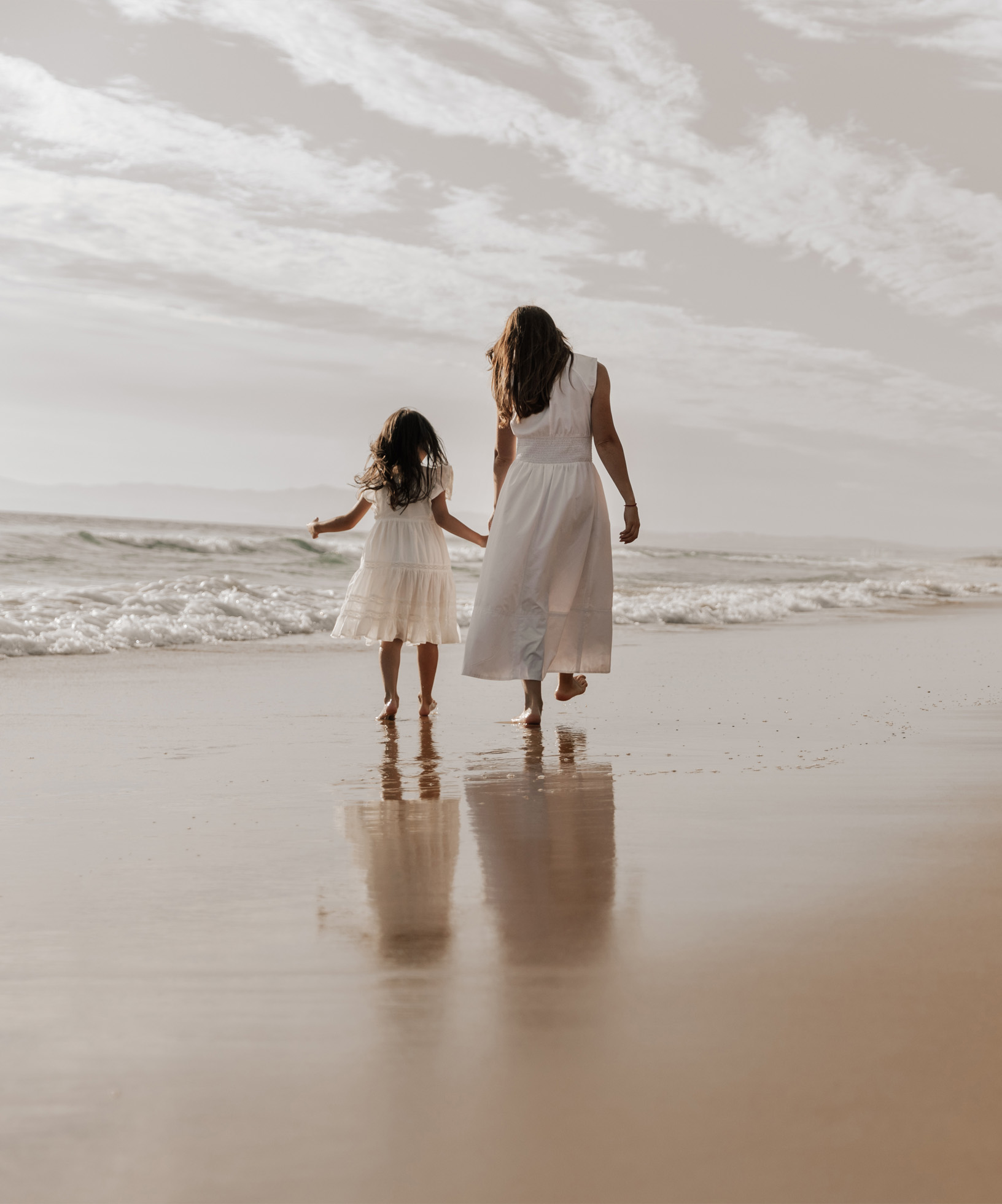 Photo d'une mère et d'une fille marchant sur la plage illustrant l'héritage intergénérationnel et le secret de famille Philosophale